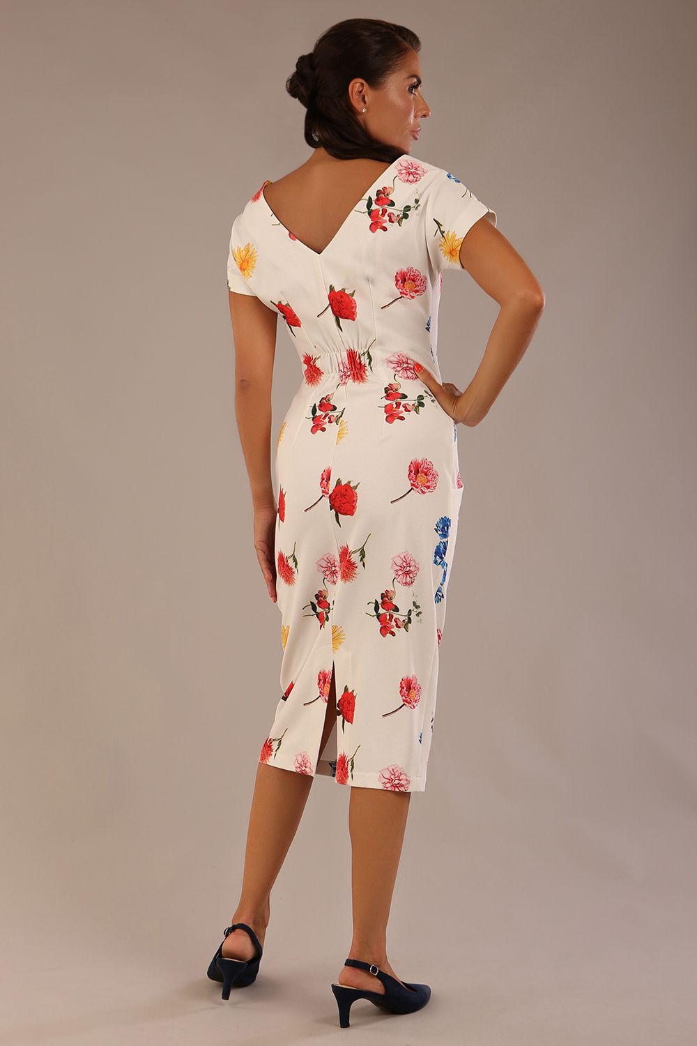 brunette model is wearing a 7002 diva catwalk Carlisle Boat Neck Short Sleeve Midi Pencil Dress in Buttercup print with side pockets back