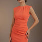 Woman wearing an orange dress against a brown background (Sea Coral)