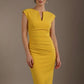 Woman wearing a yellow dress against a brown background (Mustard Yellow)
