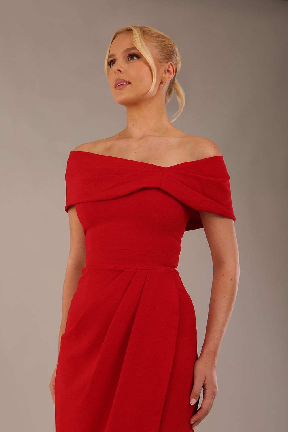 model wearing diva catwalk vegas calf length midaxi dress with wide bardot neckline and open shoulders with a large opening at the front of the skirt with pleating coming down long skirt front close up in scarlet red (Scarlet Red)