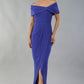 model wearing diva catwalk vegas calf length spectrum indigo midaxi dress with wide bardot neckline and open shoulders with a large opening at the front of the skirt with pleating coming down long skirt front (Spectrum Indigo)