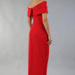 model wearing diva catwalk vegas calf length midaxi dress with wide bardot neckline and open shoulders with a large opening at the front of the skirt with pleating coming down long skirt back in scarlet red (Scarlet Red)