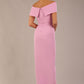 brunette model wearing diva catwalk vegas calf length dawn pink midaxi dress with wide bardot neckline and open shoulders with a large opening at the front of the skirt with pleating coming down long skirt back (Dawn Pink)