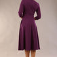 Brunette model is wearing diva catwalk casares swing dress with a keyhole neckline three quarter sleeve dress with pocket detail in imperial purple side back