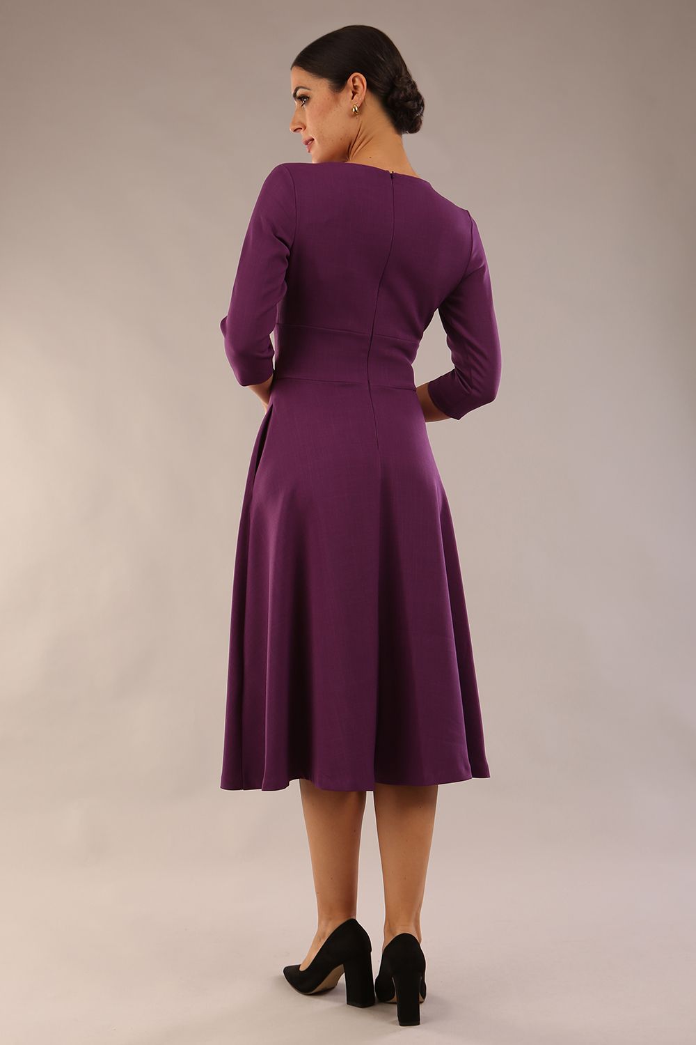 Brunette model is wearing diva catwalk casares swing dress with a keyhole neckline three quarter sleeve dress with pocket detail in imperial purple side back