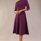 Brunette model is wearing diva catwalk casares swing dress with a keyhole neckline three quarter sleeve dress with pocket detail in imperial purple side front (Imperial Purple)