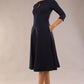 Brunette  model is wearing diva catwalk casares swing dress with a keyhole neckline three quarter sleeve dress with pocket detail in navy blue front (Navy Blue)