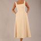 brunette model wearing a diva catwalk Tamsin Square Neckline Swing Dress sleeveless style with a midaxi  length and side pockets in Sandshell Beige colour front