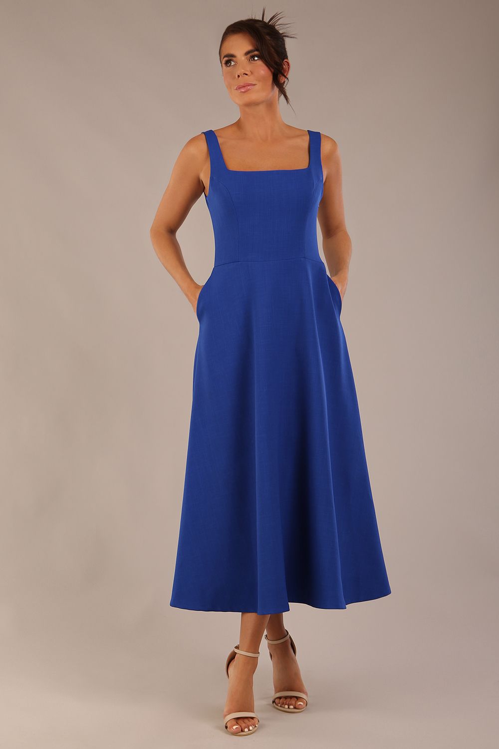 brunette model wearing a diva catwalk Tamsin Square Neckline Swing Dress sleeveless style with a midaxi  length and side pockets in cobalt blue colour front (Cobalt blue)
