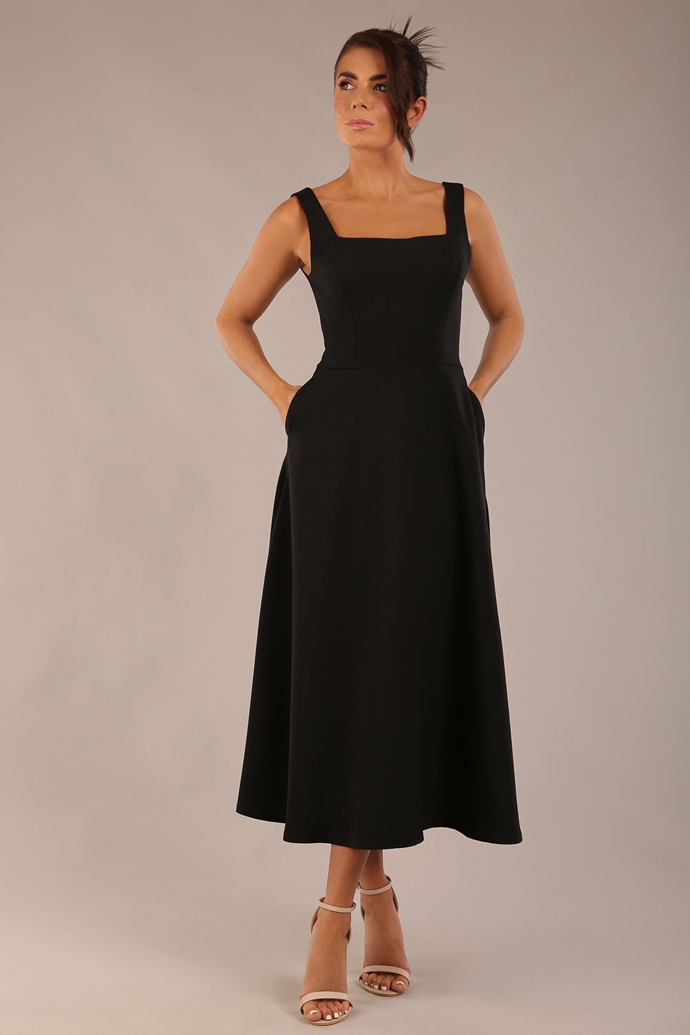 brunette model wearing a diva catwalk Tamsin Square Neckline Swing Dress sleeveless style with a midaxi  length and side pockets in Black colour front (Black)