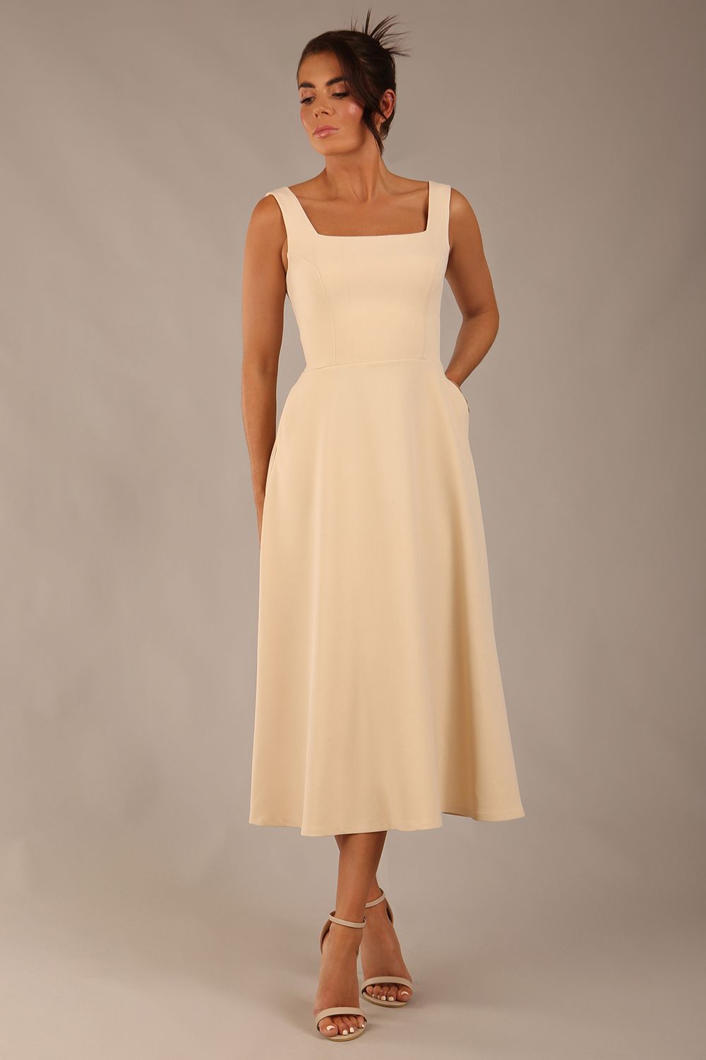 brunette model wearing a diva catwalk Tamsin Square Neckline Swing Dress sleeveless style with a midaxi  length and side pockets in Sandshell Beige colour front  (Sandshell Beige)