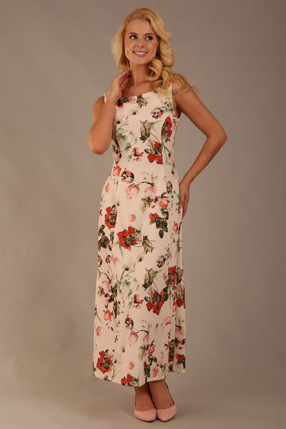 blonde model is wearing a 7000 diva catwalk Glyndebourne Sleeveless Square Neck Maxi Dress in Rose Blush print with pockets front