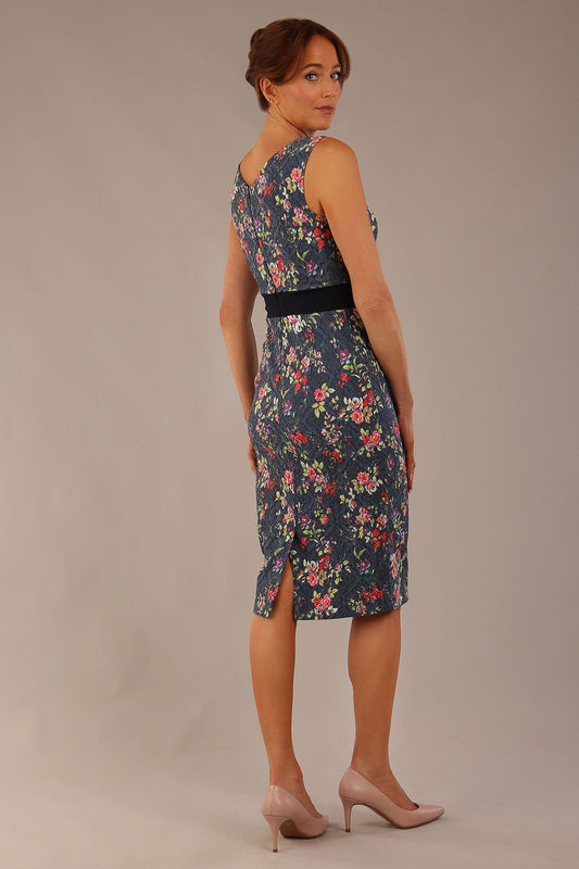 brunette model is wearing a diva catwalk June Floral Sleeveless Navy Waistband Pencil Dress in floral blue print back image