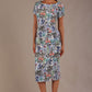brunette model is wearing a 7002 diva catwalk Carlisle Boat Neck Short Sleeve Midi Pencil Dress in water garden print with side pockets front