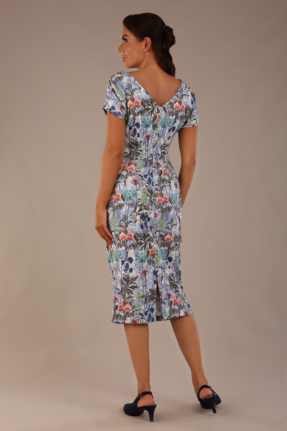 brunette model is wearing a 7002 diva catwalk Carlisle Boat Neck Short Sleeve Midi Pencil Dress in water garden print with side pockets back