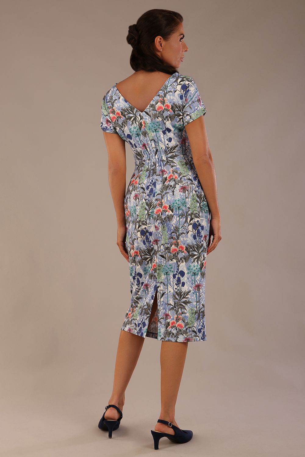 brunette model is wearing a 7002 diva catwalk Carlisle Boat Neck Short Sleeve Midi Pencil Dress in water garden print with side pockets back
