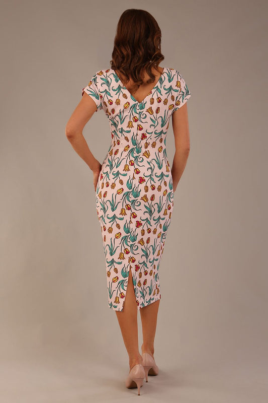 brunette model is wearing a 7002 diva catwalk Carlisle Boat Neck Short Sleeve Midi Pencil Dress in Linear Tulip print with side pockets back