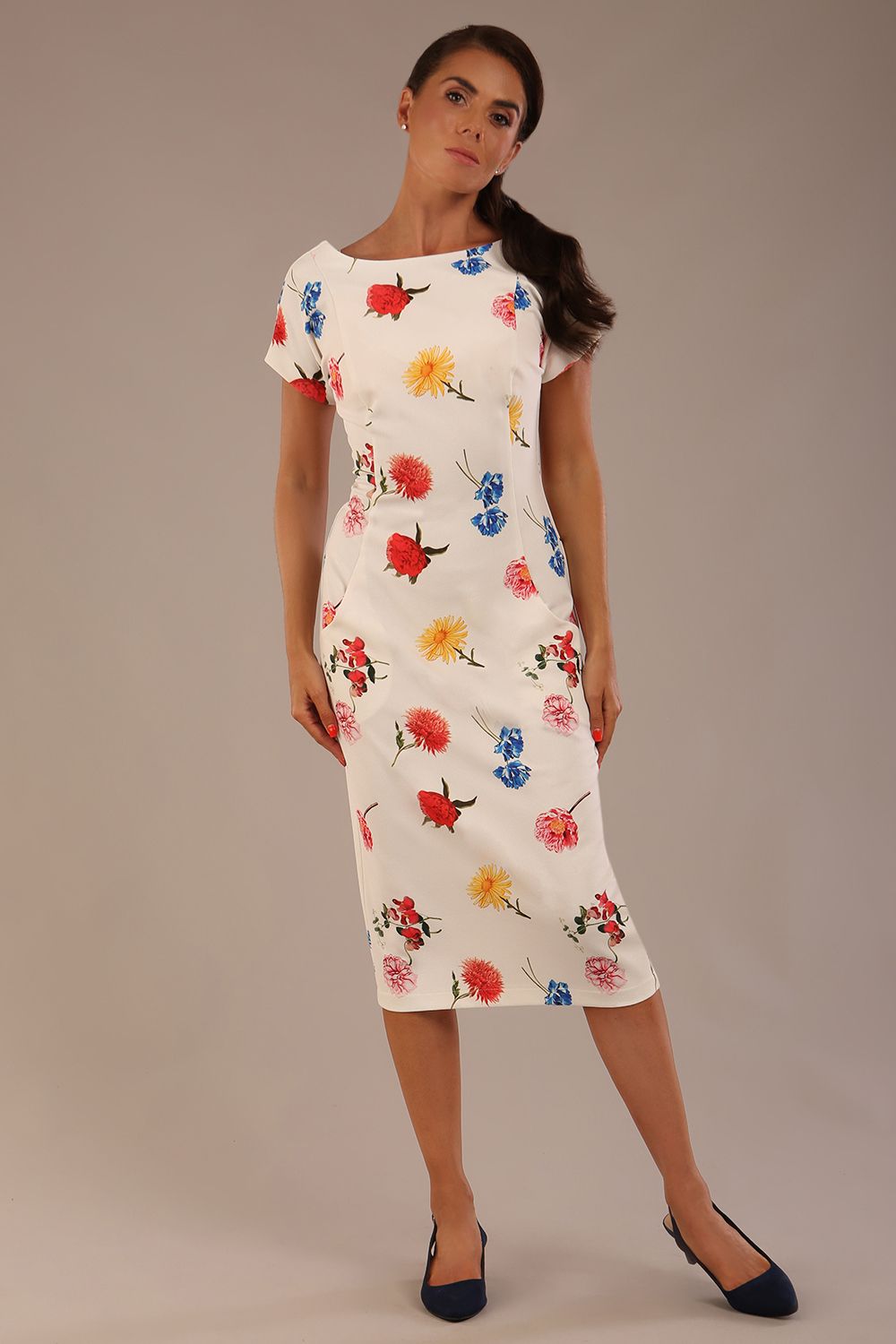 brunette model is wearing a 7002 diva catwalk Carlisle Boat Neck Short Sleeve Midi Pencil Dress in Buttercup print with side pockets front