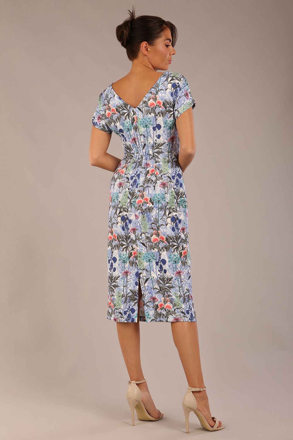 brunette model is wearing a 7002 diva catwalk Carlisle Boat Neck Short Sleeve Midi Pencil Dress in water garden print with side pockets back
