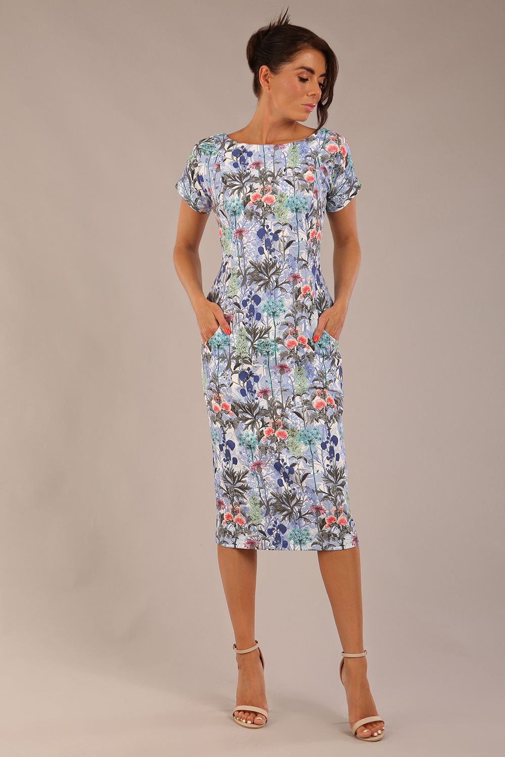 brunette model is wearing a 7002 diva catwalk Carlisle Boat Neck Short Sleeve Midi Pencil Dress in water garden print with side pockets front