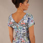 brunette model is wearing a 7002 diva catwalk Carlisle Boat Neck Short Sleeve Midi Pencil Dress in water garden print with side pockets back