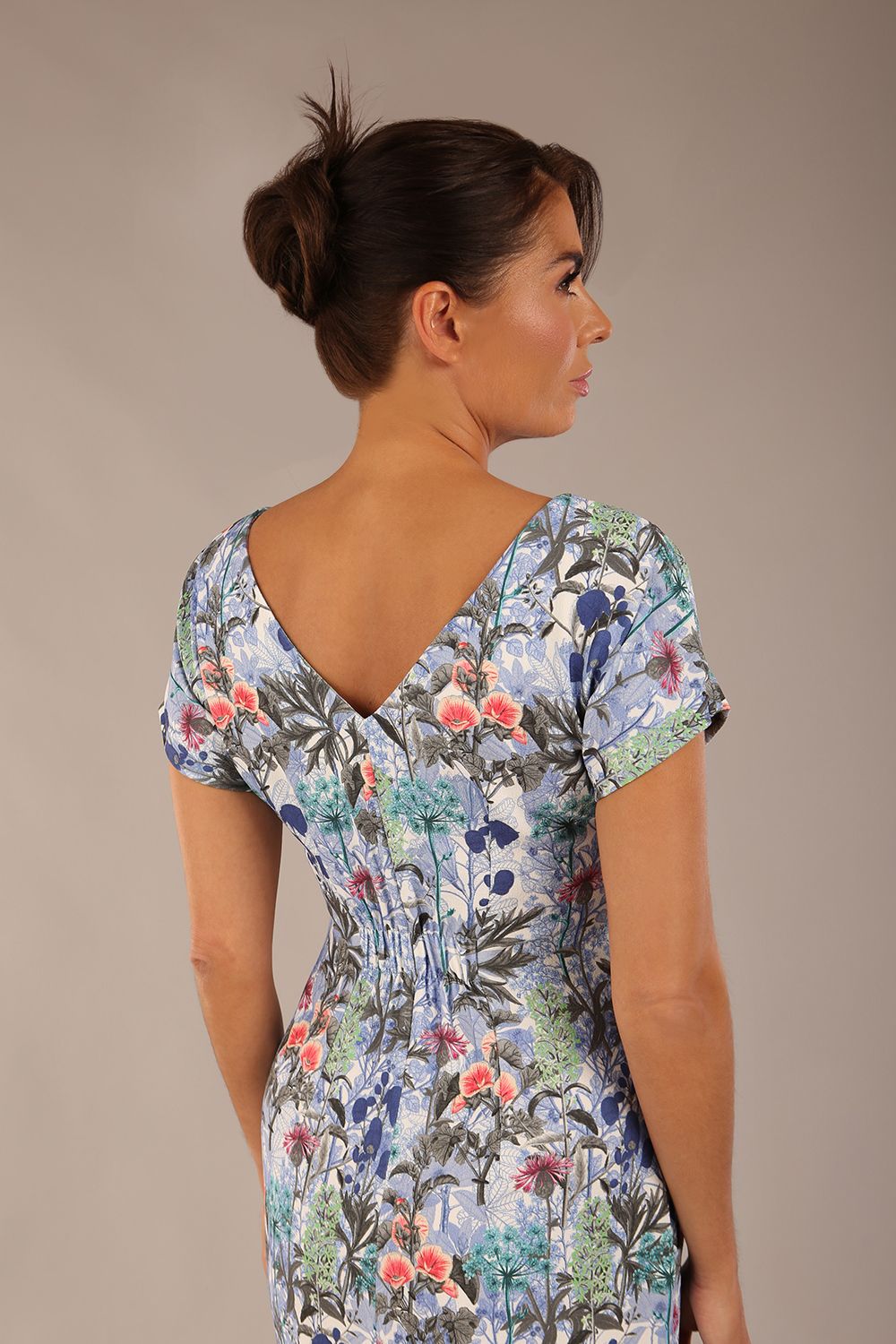 brunette model is wearing a 7002 diva catwalk Carlisle Boat Neck Short Sleeve Midi Pencil Dress in water garden print with side pockets back