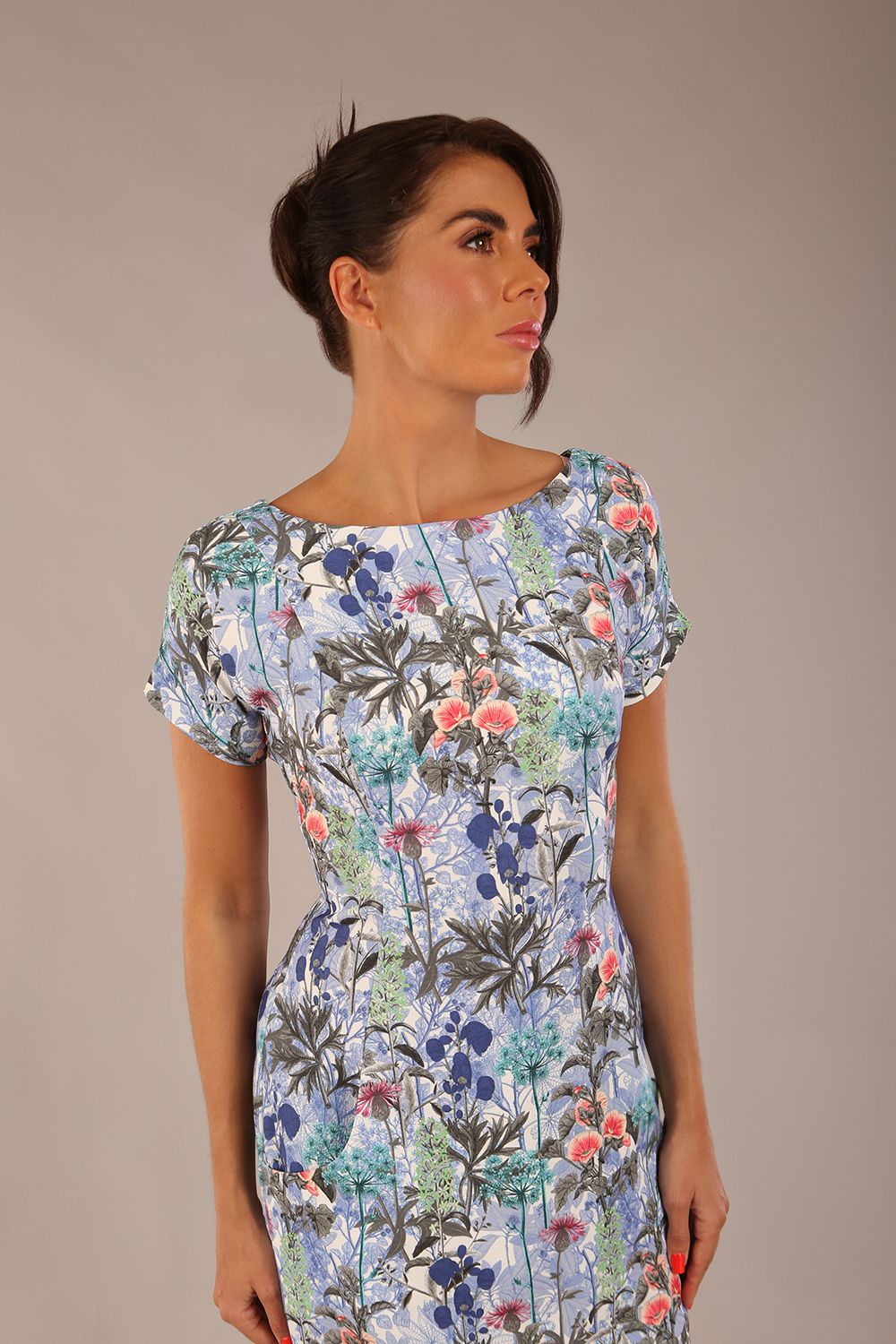 brunette model is wearing a 7002 diva catwalk Carlisle Boat Neck Short Sleeve Midi Pencil Dress in water garden print with side pockets front