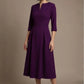 Woman wearing a diva catwalk Amanda Pleated a-line dress in a magenta pink colour against a beige background (Purple)