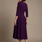 Woman wearing a diva catwalk Amanda Pleated a-line dress in a magenta pink colour against a beige background (Purple)