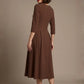 Woman wearing a diva catwalk Amanda Pleated a-line dress in a magenta pink colour against a beige background (Peppercorn Brown)