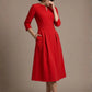 Woman wearing a diva catwalk Amanda Pleated a-line dress in a magenta pink colour against a beige background (Passion Red)