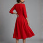 Woman wearing a diva catwalk Amanda Pleated a-line dress in a magenta pink colour against a beige background (Passion Red)