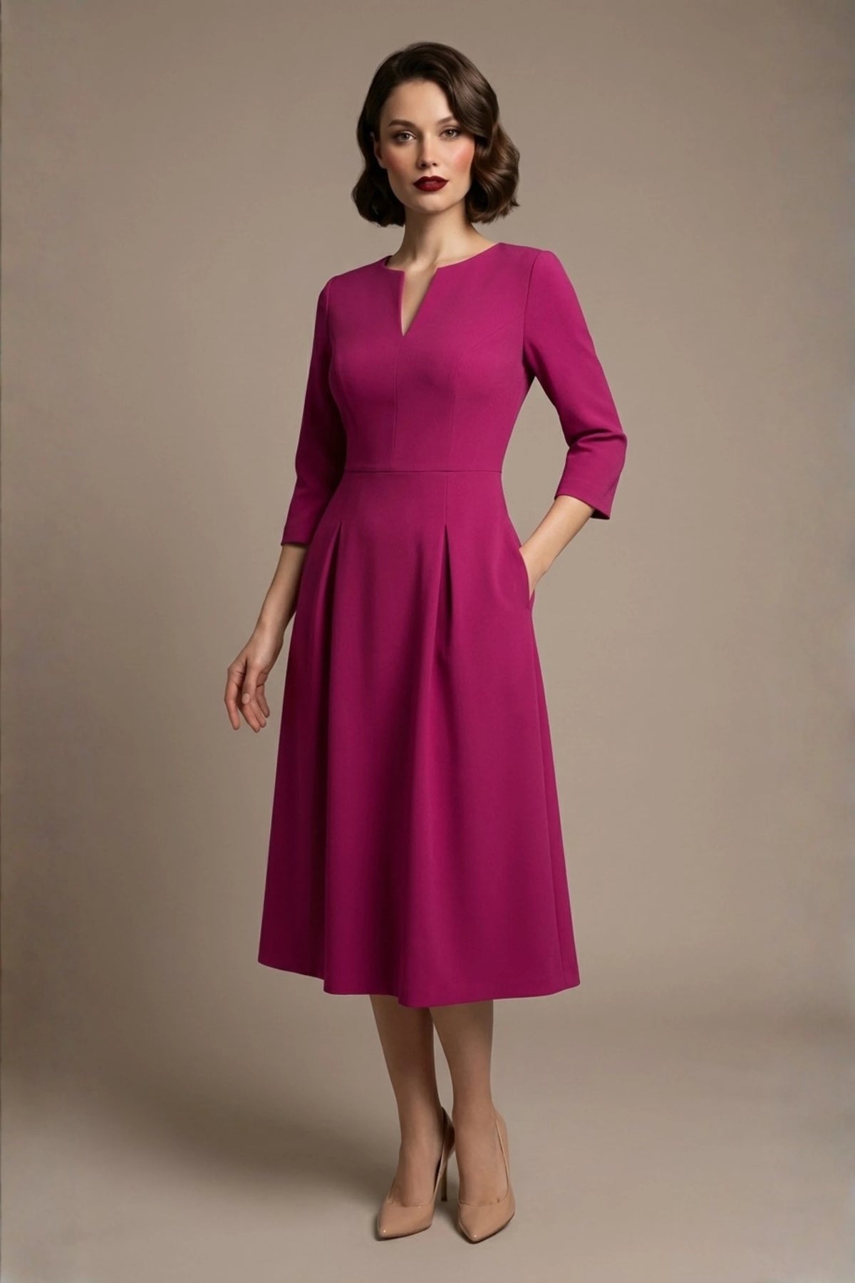 Woman wearing a diva catwalk Amanda Pleated a-line dress in a magenta pink colour with pockets against a beige background (Magenta)