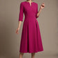 Woman wearing a diva catwalk Amanda Pleated a-line dress in a magenta pink colour against a beige background (Magenta)