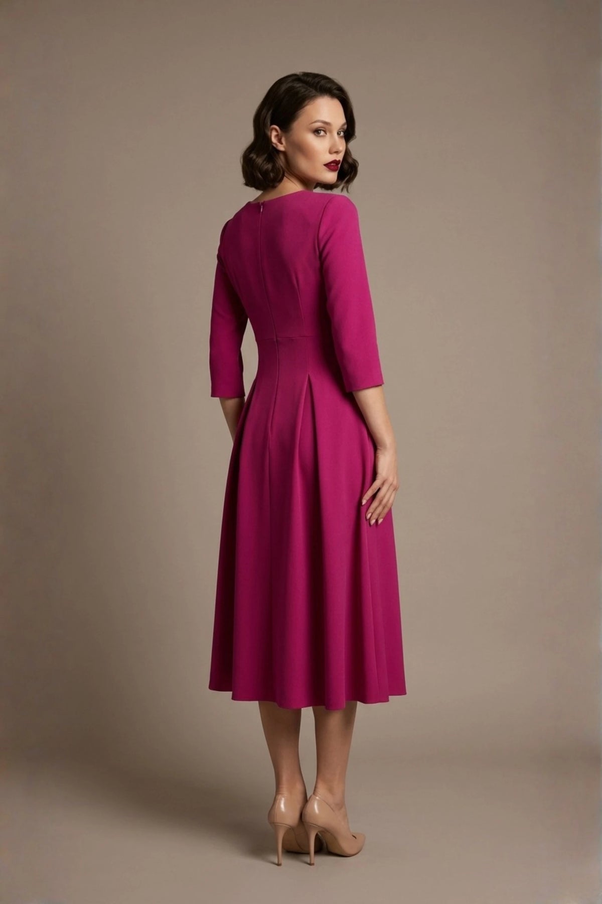 Woman wearing a diva catwalk Amanda Pleated a-line dress in a magenta pink colour against a beige background (Magenta)