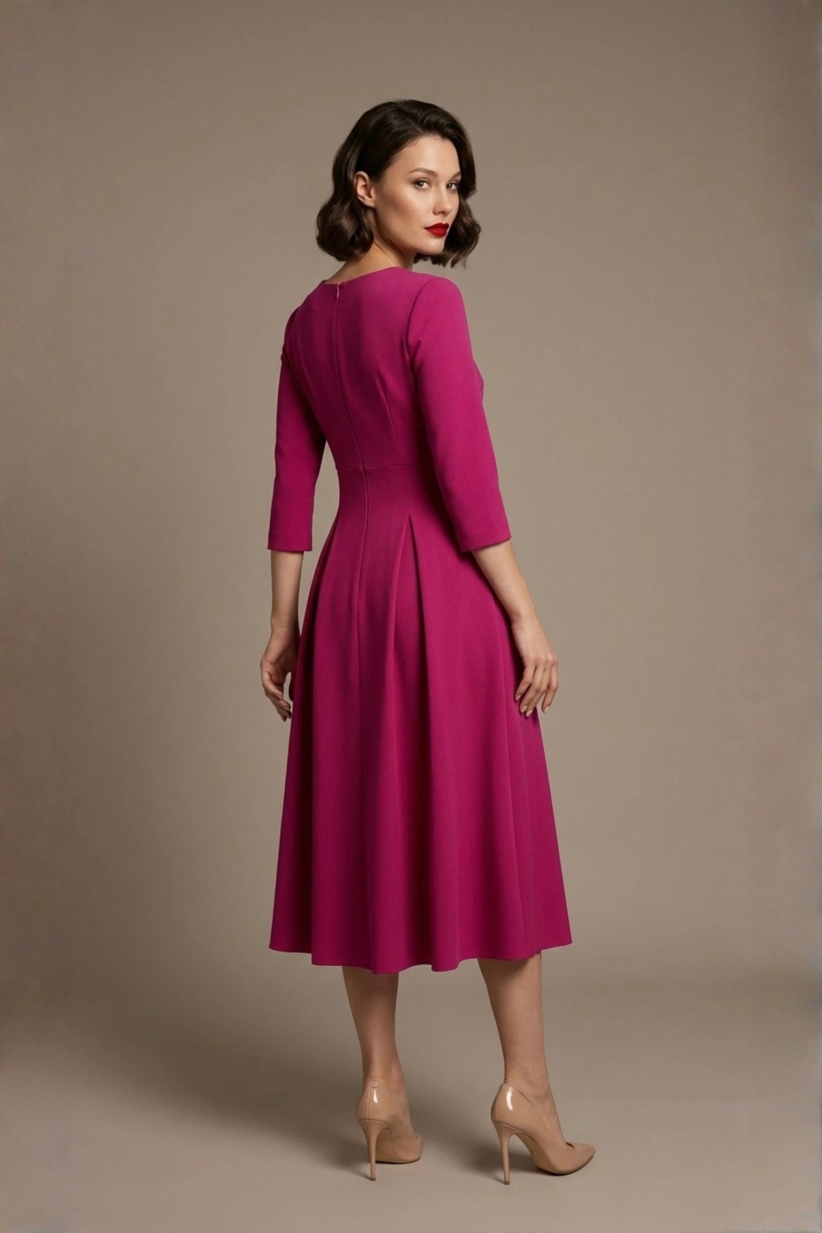 Woman wearing a diva catwalk Amanda Pleated a-line dress in a magenta pink colour against a beige background (Magenta)