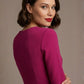 Woman wearing a diva catwalk Amanda Pleated a-line dress in a magenta pink colour against a beige background (Magenta)