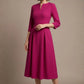 Woman wearing a diva catwalk Amanda Pleated a-line dress in a magenta pink colour against a beige background (Magenta)